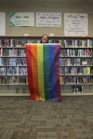 Miss Berlin standing with a gay pride flag in the CCA library.